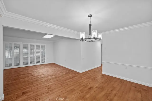 a view of empty room with wooden floor and chandelier