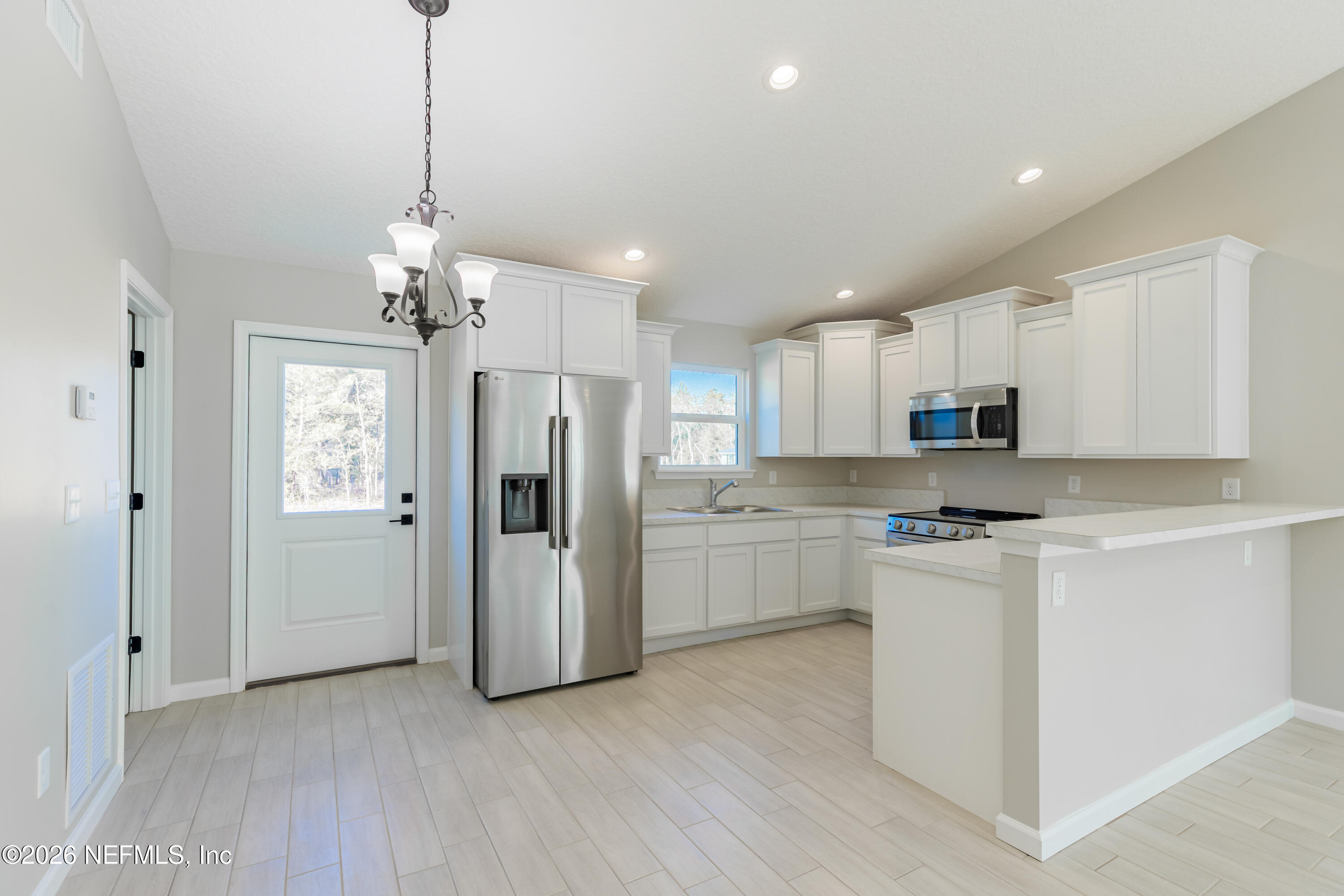 6202 Furman Avenue Keystone Heights, FL 32656 - Photo 11 of 24 a open kitchen with stainless steel appliances granite countertop a refrigerator a sink dishwasher a oven and white cabinets with wooden floor
