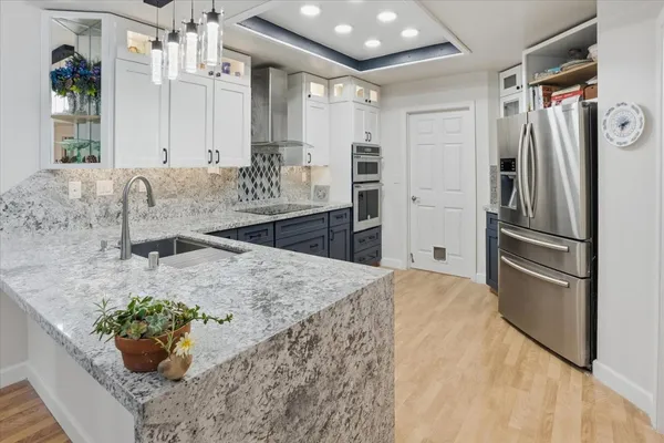 a kitchen with stainless steel appliances kitchen island granite countertop a refrigerator and a sink