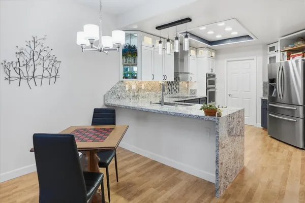 a kitchen with kitchen island stainless steel appliances a table chairs and wooden floor