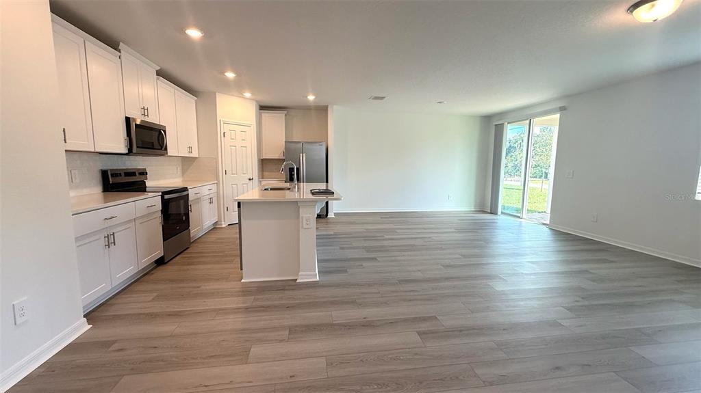 4543 Sidesaddle Trail St. Cloud, FL 34772 - Photo 3 of 19 a kitchen with stainless steel appliances kitchen island granite countertop a stove a sink and white cabinets with wooden floor