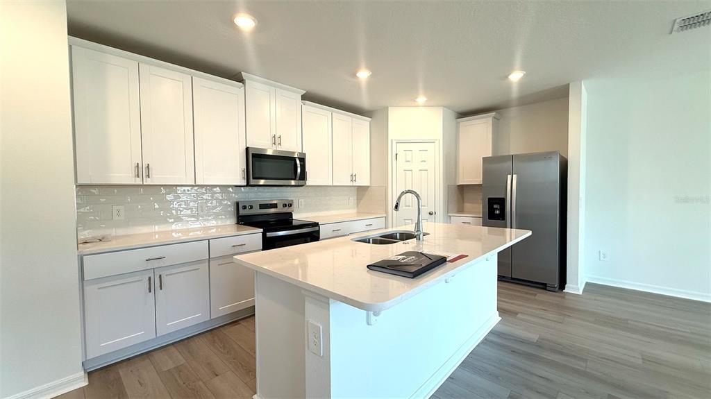 4543 Sidesaddle Trail St. Cloud, FL 34772 - Photo 4 of 19 a kitchen with a sink a microwave a refrigerator and cabinets