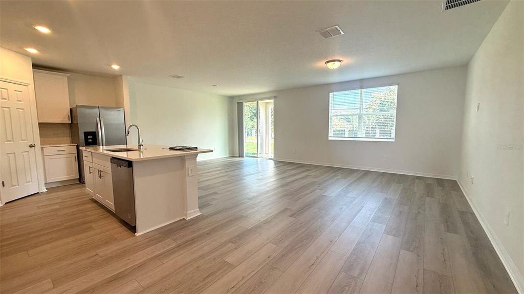 4543 Sidesaddle Trail St. Cloud, FL 34772 - Photo 5 of 19 a kitchen with stainless steel appliances kitchen island hardwood floor sink and stove