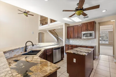 a kitchen with stainless steel appliances granite countertop a sink a stove and a refrigerator