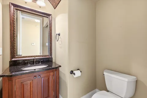 a bathroom with a granite countertop toilet a sink and mirror