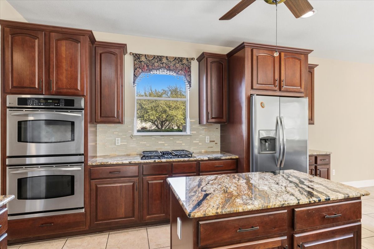 111 Whitley Drive Austin, TX 78738 - Photo 10 of 38 a kitchen with kitchen island granite countertop wooden cabinets and stainless steel appliances