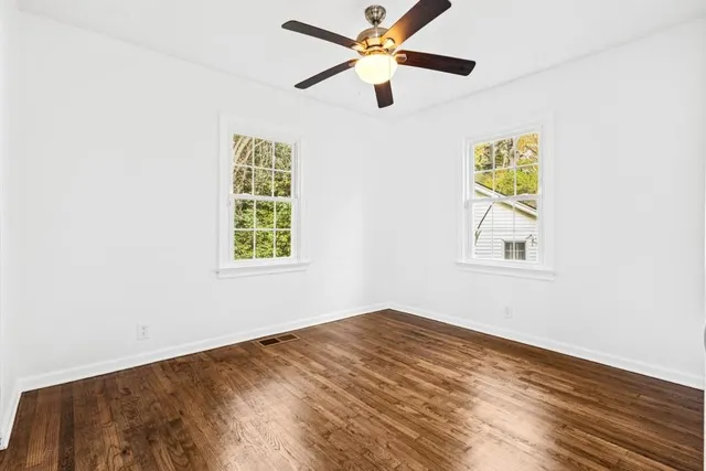 a view of empty room with wooden floor and fan