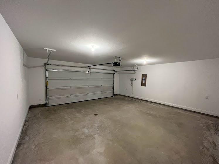 1408 Rendyn Street Anna, TX 75409 - Photo 21 of 23 Enclosed garage with a white sectional door, exposed overhead door mechanism, concrete flooring, and ceiling-mounted lighting