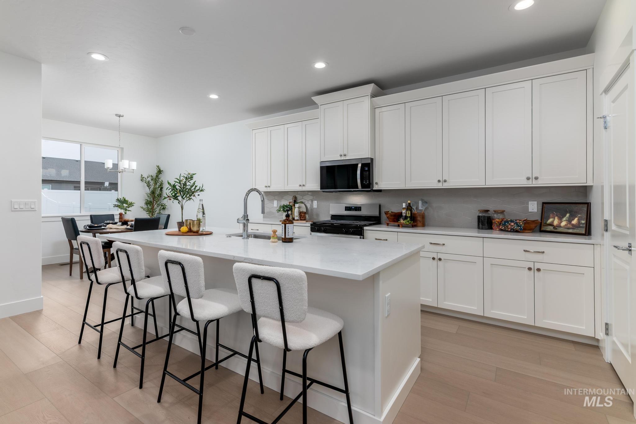 1940 West Chokecherry Avenue Middleton, ID 83644 - Photo 4 of 12 Kitchen with a breakfast bar, white cabinetry, stainless steel appliances, a center island with sink, and light wood-style flooring