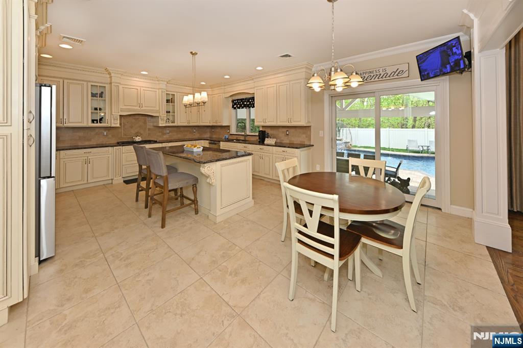 106 Arnot Place Paramus, NJ 07652 - Photo 14 of 48 a kitchen with kitchen island a dining table and chairs