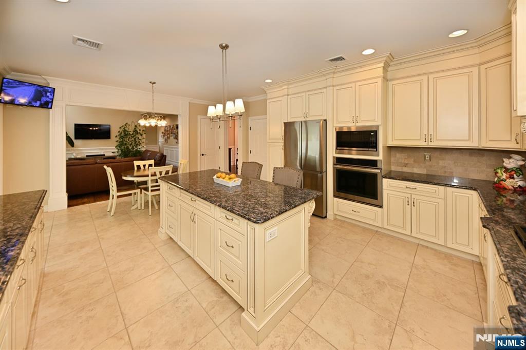 106 Arnot Place Paramus, NJ 07652 - Photo 17 of 48 a kitchen with stainless steel appliances granite countertop a stove top oven a sink dishwasher a dining table and chairs with wooden floor