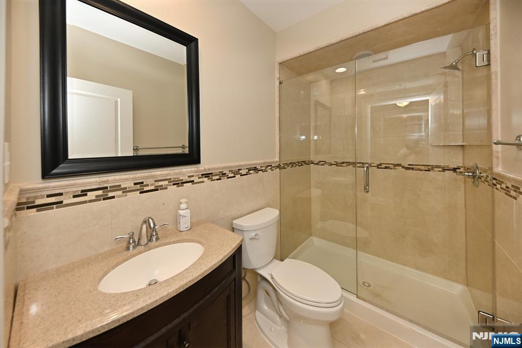 106 Arnot Place Paramus, NJ 07652 - Photo 32 of 48 a bathroom with a granite countertop sink toilet a mirror and shower