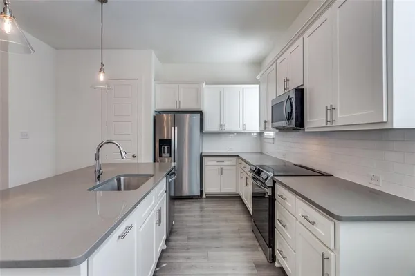 a kitchen with stainless steel appliances granite countertop a sink stove a refrigerator and cabinets with wooden floor