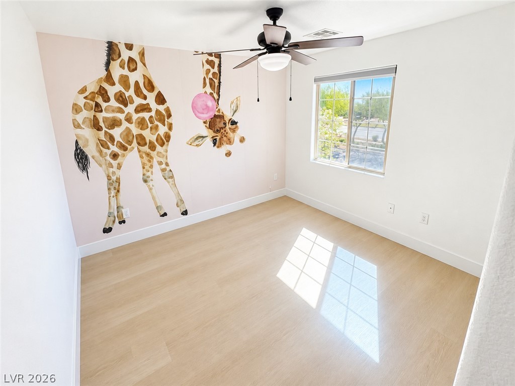 Natural light streams across smooth plank flooring in this cheerful secondary bedroom.