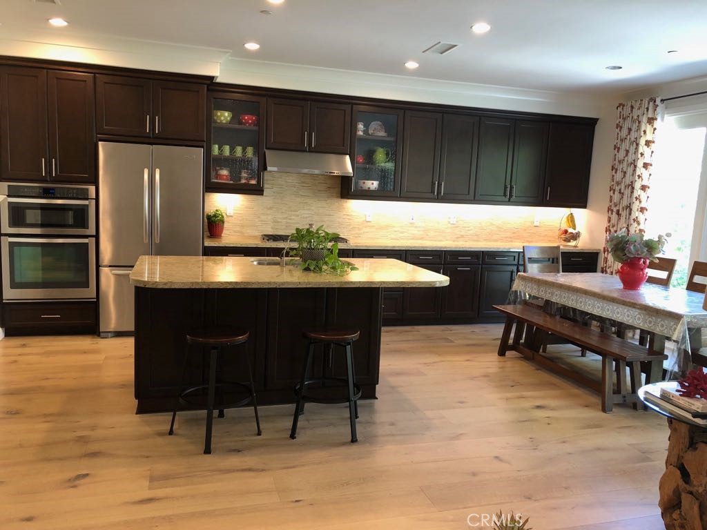 88 Lupari Irvine, CA 92618 - Photo 5 of 33 a kitchen with stainless steel appliances kitchen island granite countertop a table chairs and a refrigerator