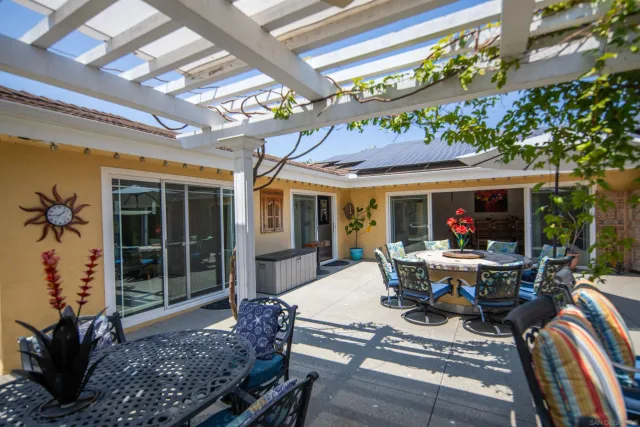 a view of a patio with couches table and chairs under an umbrella with a barbeque