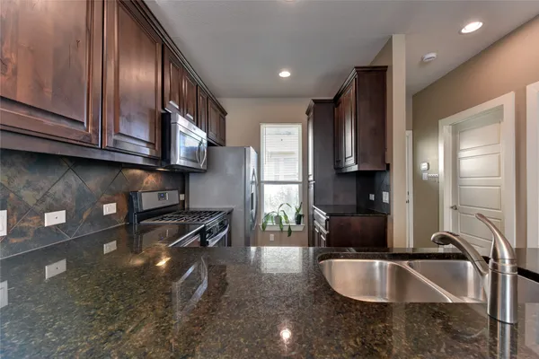 a kitchen with granite countertop a sink stainless steel appliances and cabinets