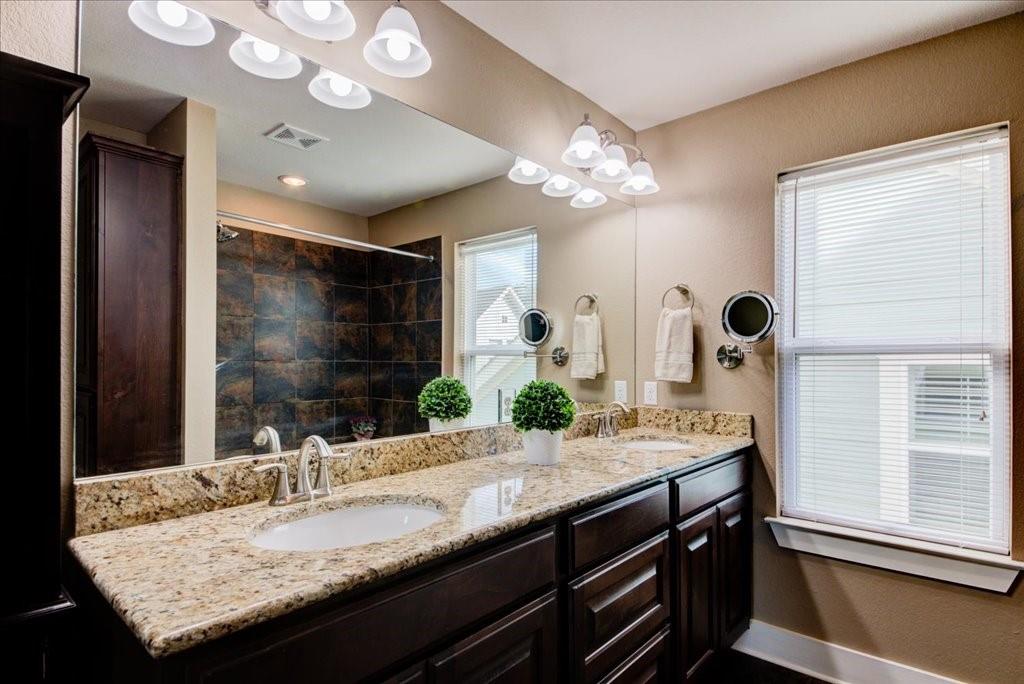 12212 Tawny Farms Road, Unit 142 Austin, TX 78748 - Photo 16 of 38 a bathroom with a granite countertop sink a large mirror and a window