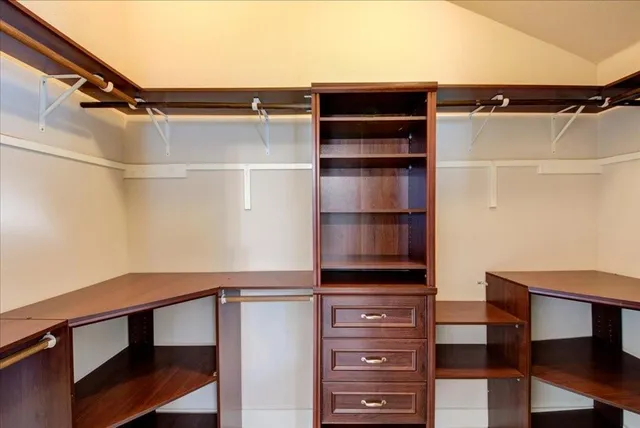 a view of walk in closet with clothes and shoes