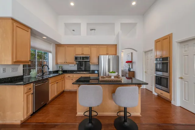 a kitchen with stainless steel appliances granite countertop a table chairs microwave and sink