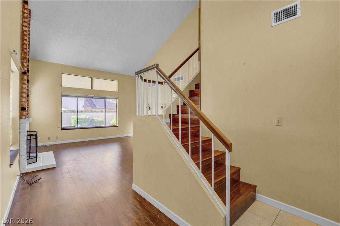 6440 Hartwood Road Las Vegas, NV 89108 - Photo 4 of 59 Rich hardwood floors welcome you into this living area, featuring a cozy fireplace and a grand staircase.