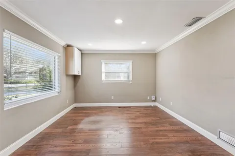 a view of an empty room with wooden floor and a window