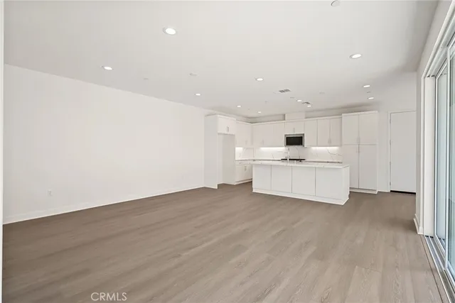a view of a kitchen with white cabinets and wooden floor