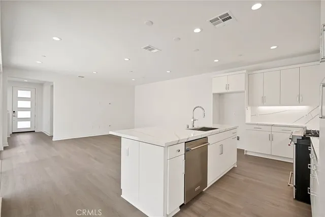 a kitchen that has a lot of white cabinets and wooden floor