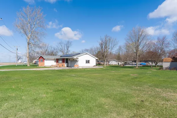a front view of a house with a big yard and a large tree