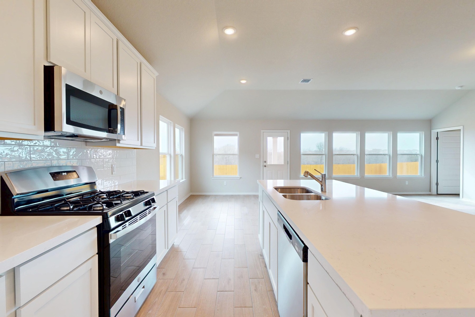 20009 Hirono Drive Manor, TX 78653 - Photo 7 of 39 a kitchen with stainless steel appliances granite countertop a stove a sink and a microwave