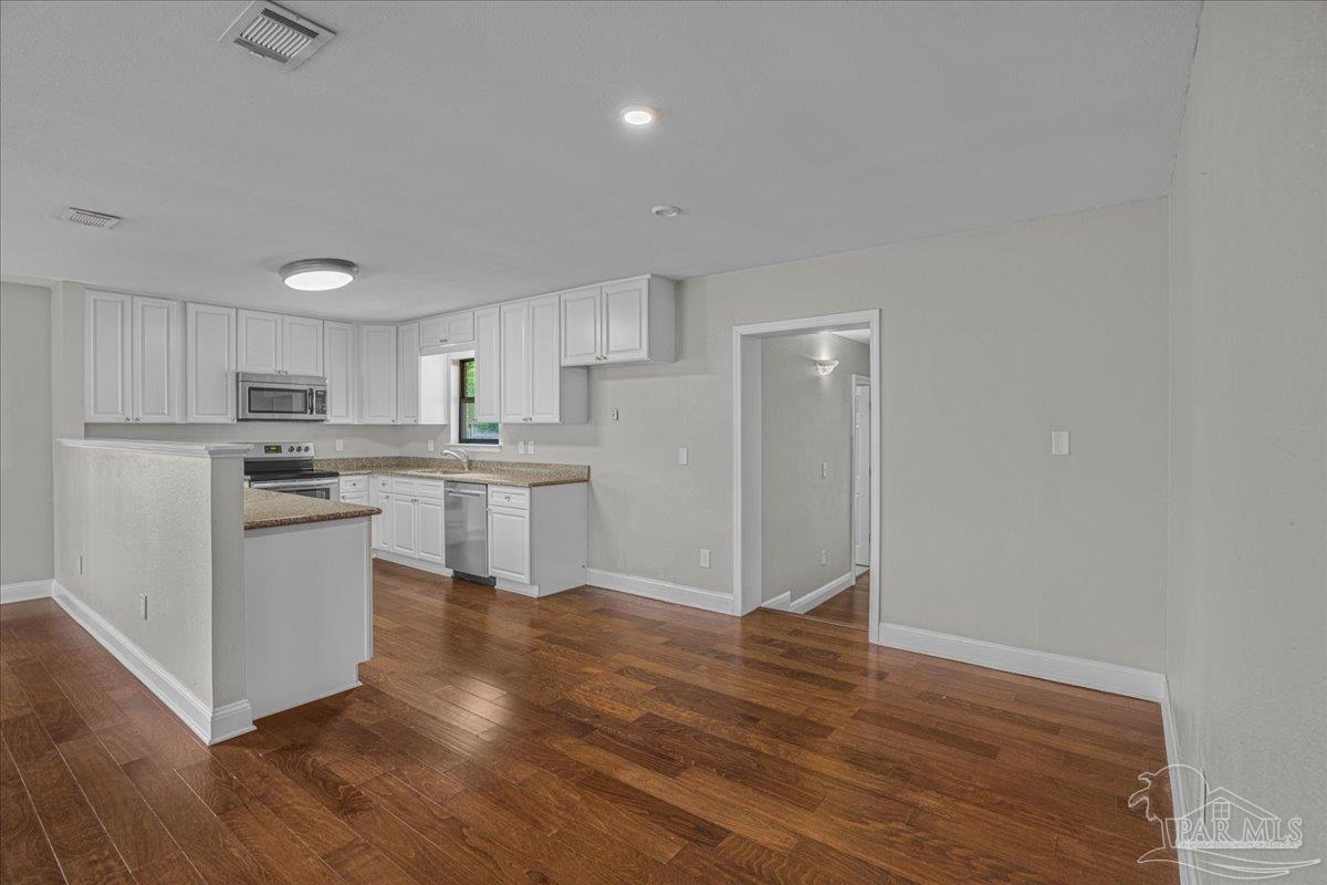 5946 Greenfield Street Pace, FL 32571 - Photo 16 of 42 a kitchen with white cabinets and stainless steel appliances