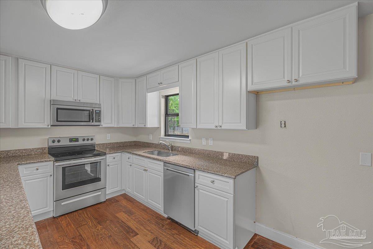 5946 Greenfield Street Pace, FL 32571 - Photo 21 of 42 a kitchen with granite countertop white cabinets and white appliances
