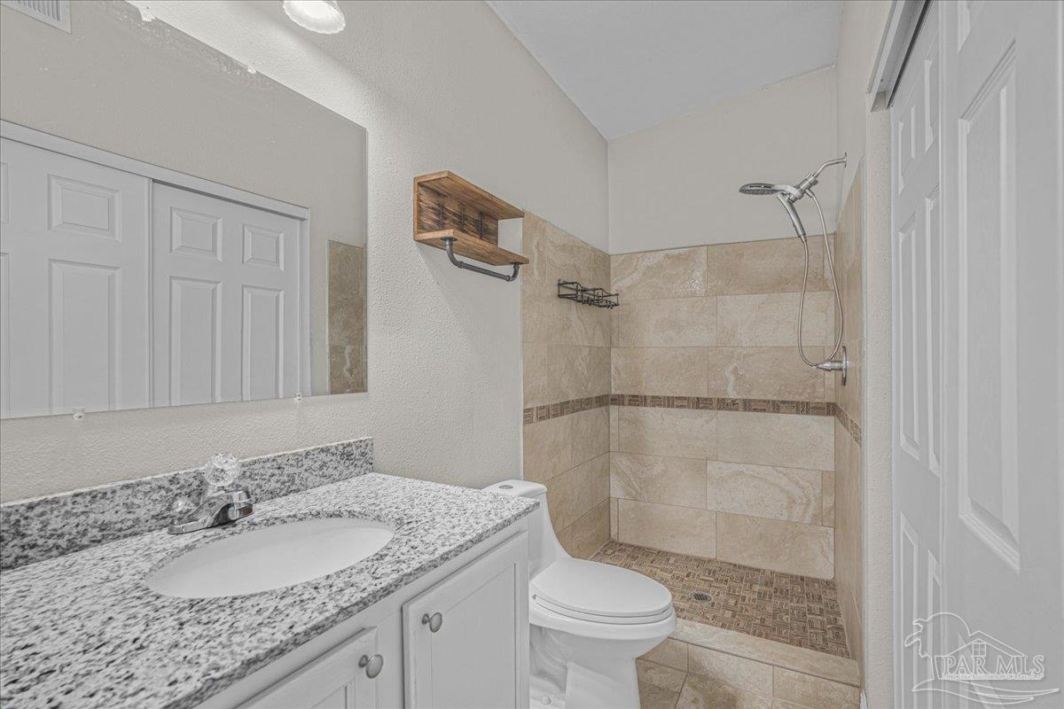 5946 Greenfield Street Pace, FL 32571 - Photo 26 of 42 a bathroom with a granite countertop sink toilet and shower