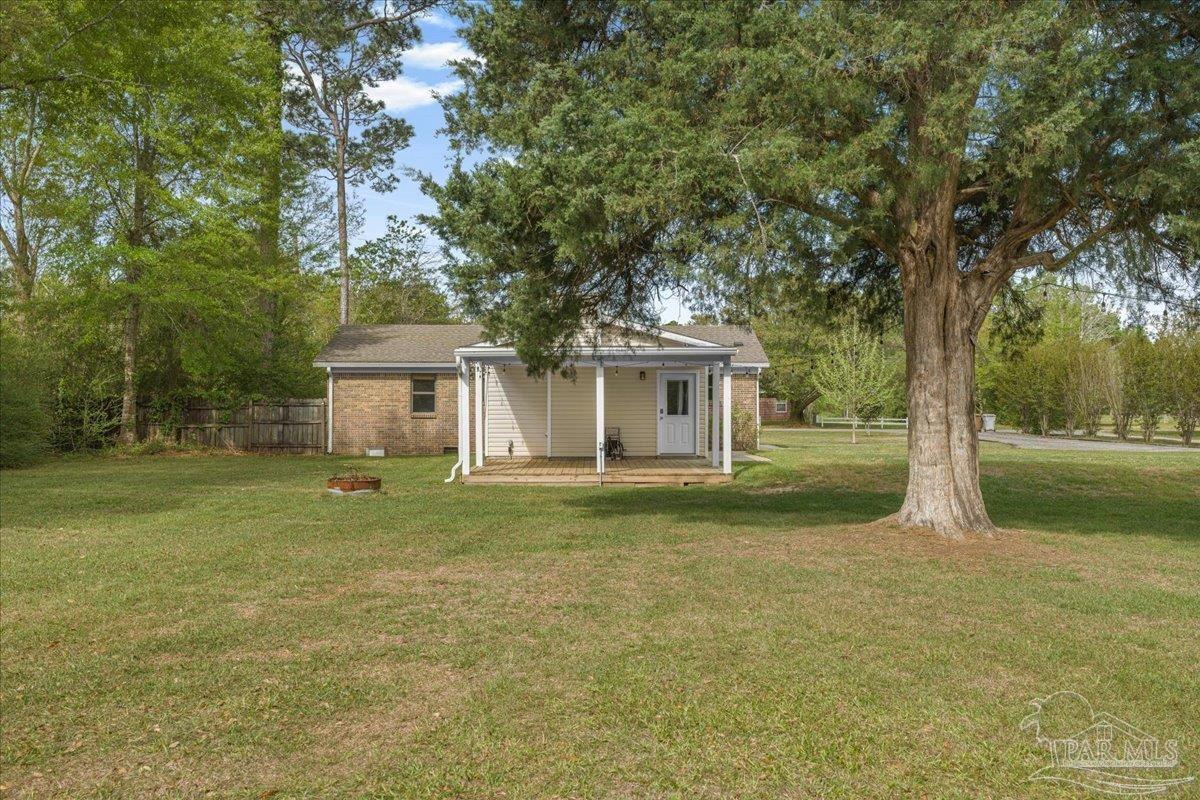 5946 Greenfield Street Pace, FL 32571 - Photo 3 of 42 a front view of a house with a garden and trees