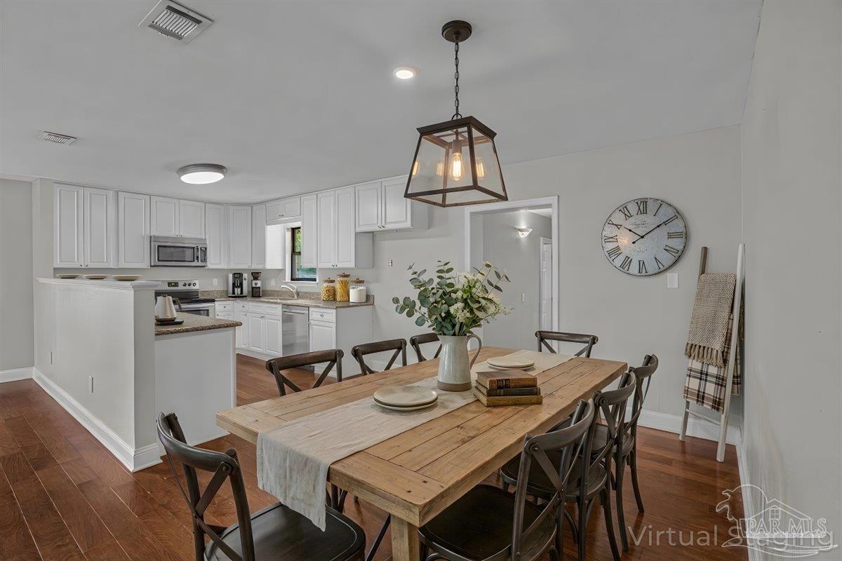 5946 Greenfield Street Pace, FL 32571 - Photo 5 of 42 a kitchen with stainless steel appliances granite countertop a dining table chairs refrigerator and cabinets