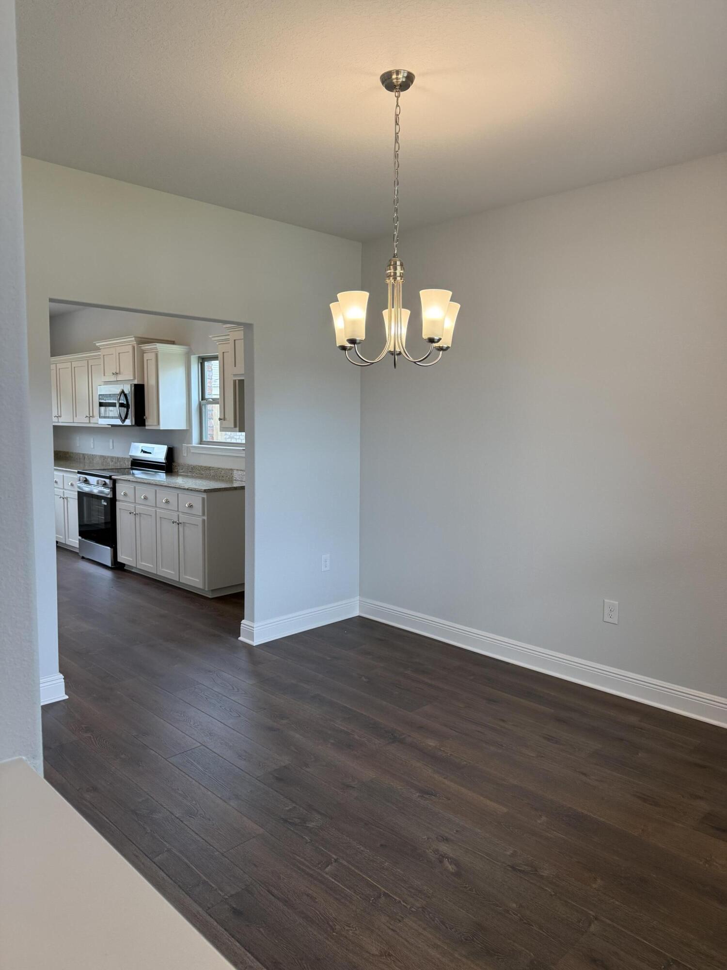 185 Ridgeway Circle Crestview, FL 32536 - Photo 7 of 30 a view of a kitchen with a stove wooden floor and a chandelier