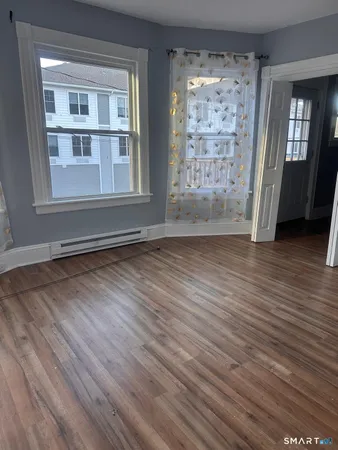a view of an empty room with wooden floor and a window