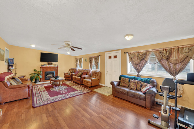977 23rd Street Ogden, UT 84401 - Photo 17 of 29 Living room featuring a glass covered fireplace, light wood-style flooring, ceiling fan, and a textured ceiling