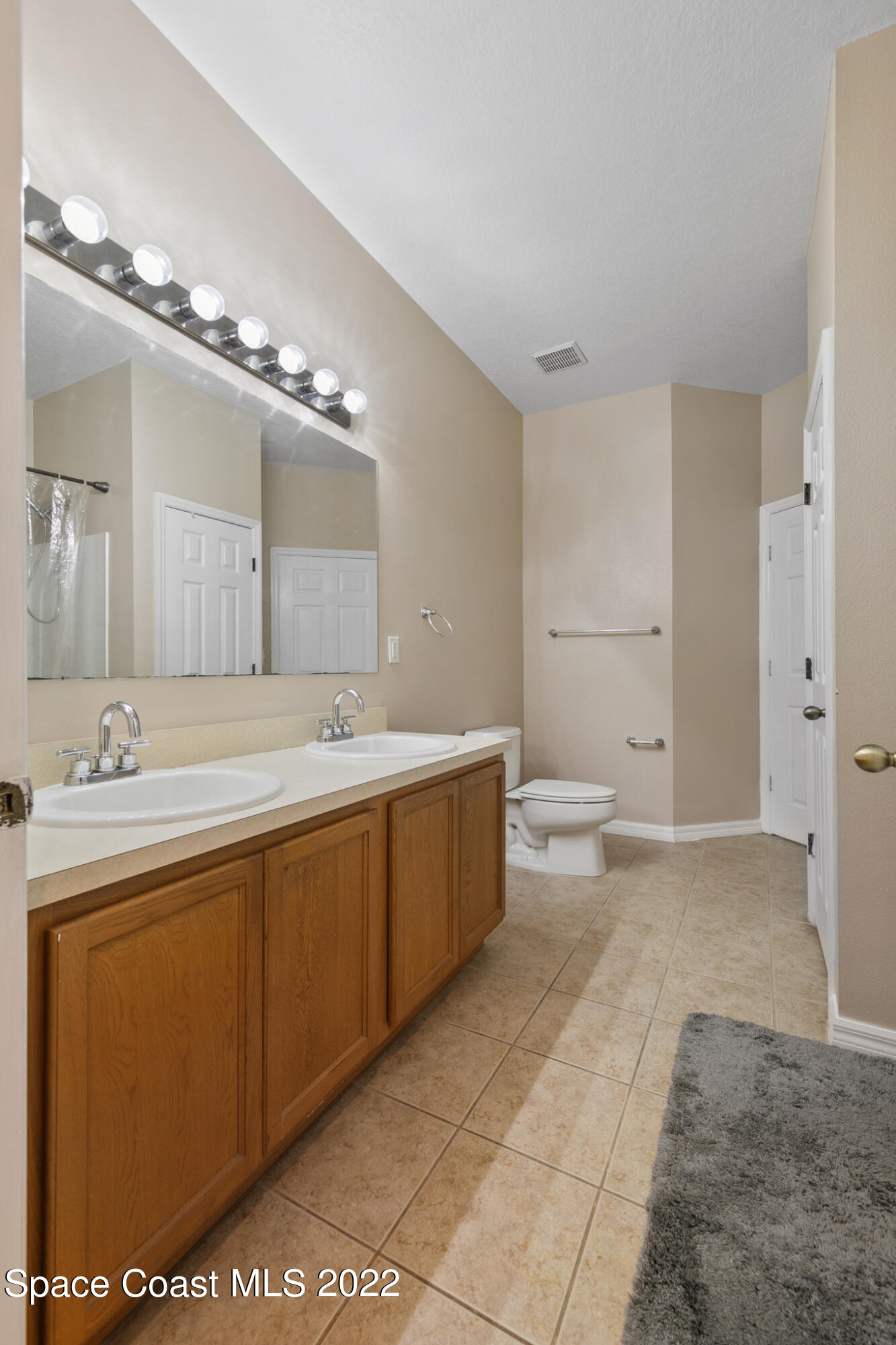 1963 Jupiter Boulevard Southwest Palm Bay, FL 32908 - Photo 24 of 42 a spacious bathroom with a double vanity sink a mirror and a toilet