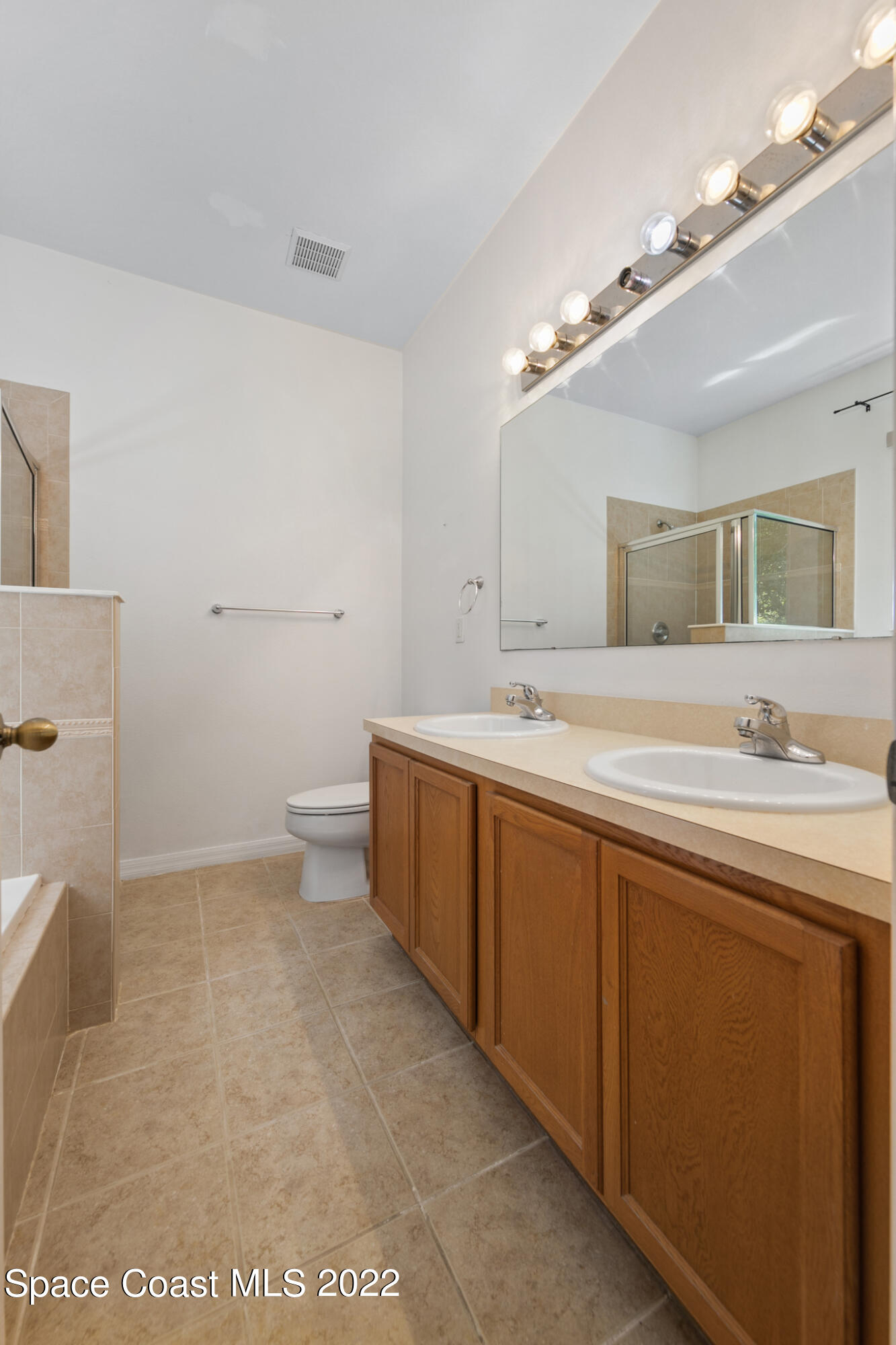 1963 Jupiter Boulevard Southwest Palm Bay, FL 32908 - Photo 31 of 42 a spacious bathroom with a double vanity sink a mirror and a toilet