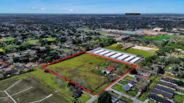 an aerial view of a tennis ground and a cars park side of the road