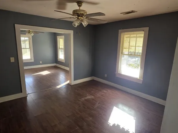 a view of an empty room with a window and wooden floor