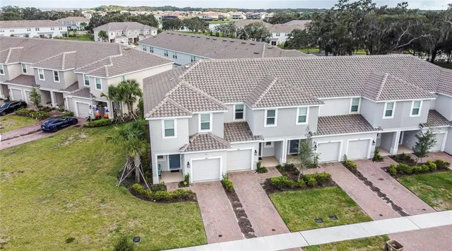 an aerial view of residential houses with yard and mountain view in back