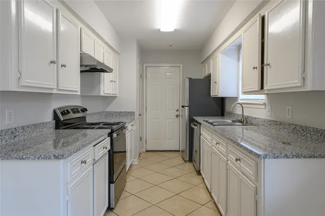 a kitchen with granite countertop a sink stove and cabinets