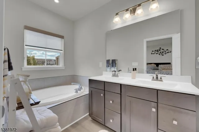 a bathroom with a tub double vanity sink and mirror