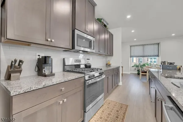a kitchen with granite countertop stainless steel appliances sink stove top oven and cabinets