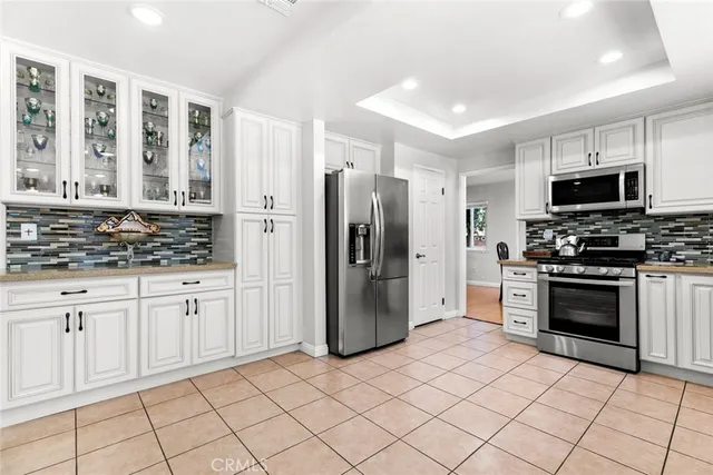 a kitchen with white cabinets appliances a sink and a window
