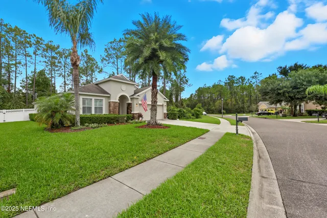 a front view of a house with a yard and palm trees