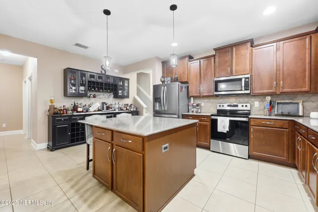a kitchen with stainless steel appliances granite countertop a stove a sink a refrigerator and a microwave