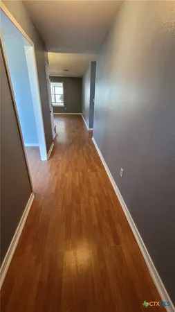 a view of an empty room with window and wooden floor